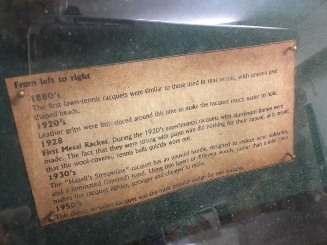 アンティークなテニスラケットの歴史と変遷について解説している彫刻が収められた額装