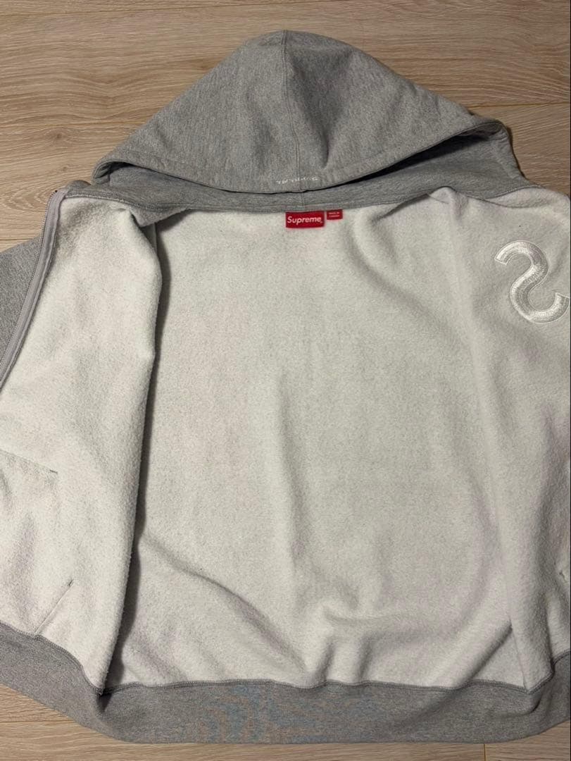 Sの刺繍が特徴のグレーのフルジップパーカー。
