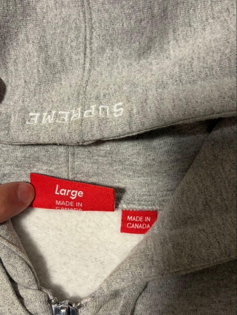 Sの刺繍が特徴のグレーのフルジップパーカー。